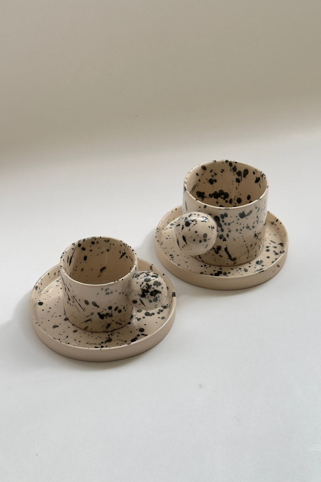 Handmade beige stoneware mug with black splash glaze by Doppiocotto