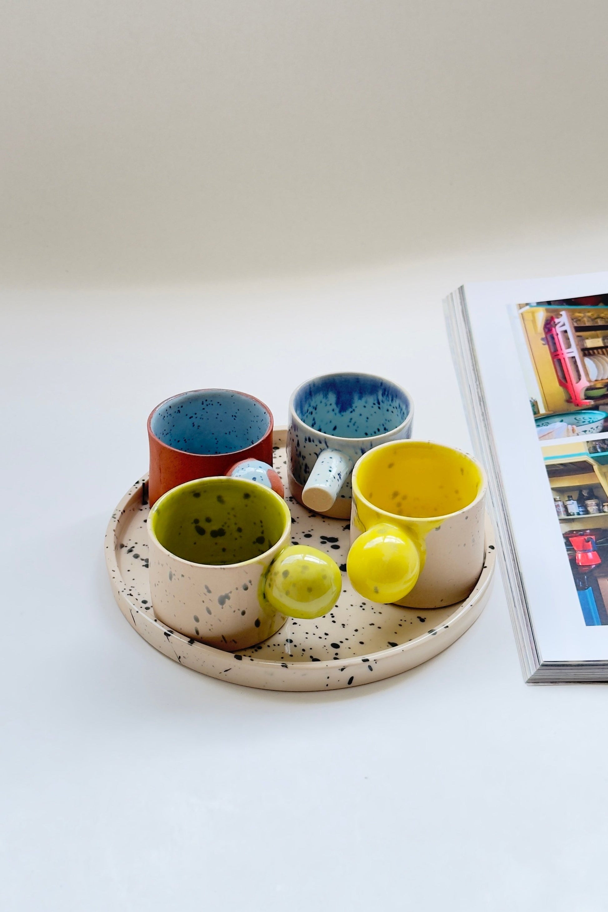 Colourful handmade espresso cups displayed on decorative serving tray