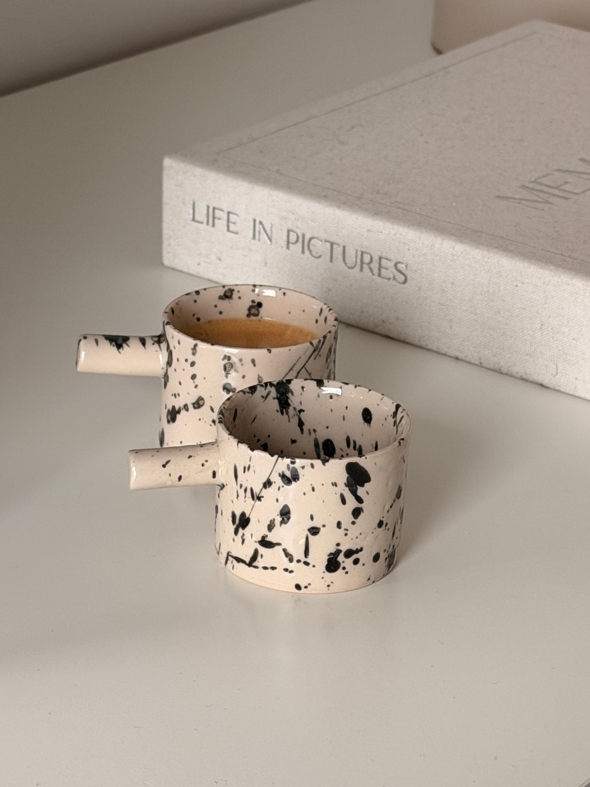 Handmade ceramic espresso cups with black splash glaze and coffee